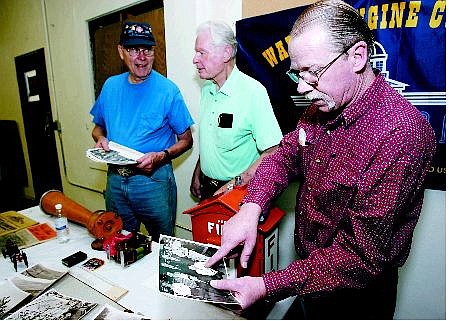 Chad Lundquist/Nevada Appeal  Veteran firefighter Kani Shannon, points to former fire chief Les Groth in a photo of the original members of the Warren Engine Company No. 1, while Les Groth, middle, and his brother George Groth, left, look over historical items from the old Warren Engine Company on Thursday.