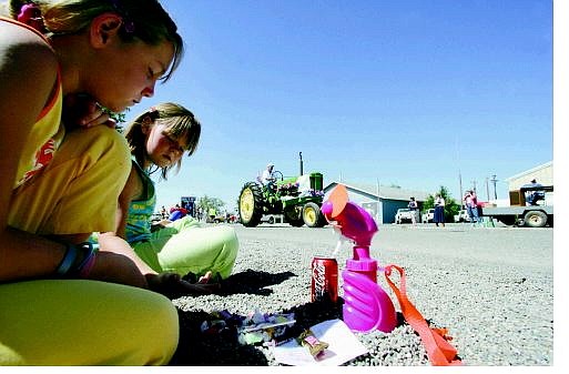 BRAD HORN/Nevada Appeal Silver Springs sisters Skyler Ness, 11, left, and Ashley, 9, count their candy while Hale Bennett drives his tractor during the parade on Fort Churchill Street on Saturday. The Founders Day Parade celebrated the anniversary of the Silver Springs community.