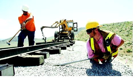 BRAD HORN/Nevada Appeal Richard Carney, left, drives in railroad spikes, while Shawn Dornan lifts a railroad tie. Crews began laying tracks for the historic Virginia &amp; Truckee Railway on Wednesday.