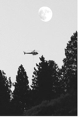 Chad Lundquist/Nevada Appeal A firefighting helicopter flies past the nearly full moon Monday evening over the Genoa blaze area.
