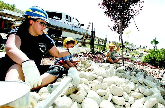 BRAD HORN/Nevada Appeal Anita Hass and her sons Justin, 7, center, and Matthew, 5, of Washoe Valley, help clear rocks from a space outside the Alderson&#039;s home that will be covered with a plastic tarp to prevent weed growth. Hass, a criminal justice major, is a volunteer firefighter in Pleasant Valley.