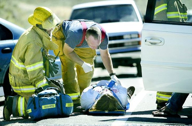 Cathleen Allison/Nevada Appeal Firefighters tend to an unidentified Carson City girl who was injured in a three-car accident on Edmonds Drive near Butti Way Tuesday afternoon. Four people were taken to Carson-Tahoe Hospital for treatment and one was taken by Care Flight to Washoe Medical Center.