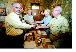 Detective Steve von Rumpf, from left clockwise, ex-sheriff Pat Whitten, Bill Beeson, artistic director at Piper&#039;s Opera House, and Henry Kilmer, treasurer at Piper&#039;s Opera House, display a bottle at Cafe Del Rio in Virginia City on Thursday. The bottle was stolen during an archaeological dig back in 1999 at the opera house.   BRAD HORN/Nevada Appeal