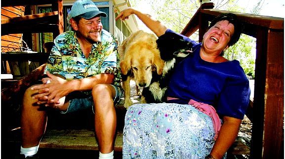 BRAD HORN/Nevada Appeal Jacqui and Gene LaVoie sit on the porch of their Stagecoach home with their dogs Trucker, left, and Sadie on Wednesday morning. The LaVoies have offered their trailer and five-acre lot to Hurricane Katrina evacuees. The LaVoies said, besides having plenty of room and a functioning trailer, victims of the Gulf Coast crisis can bring their animals. Their property also features a swimming pool.