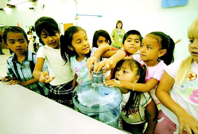BRAD HORN/Nevada Appeal From left, Tony Hernandez, Edith Cervantes, Andrea Merlin, Fernanda Solorio, Ramon Rojas, Maricela Orozco, Miriam Torres and Jordyn Pinochi, all 6, fill a water bottle with change and dollar bills during lunch on Thursday at Empire Elementary School.