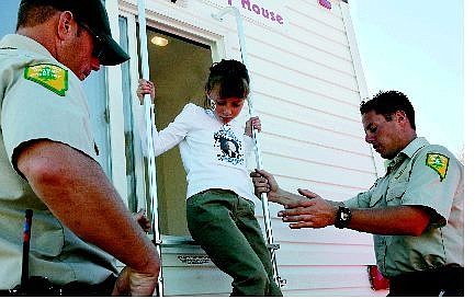 Nevada Division of Forestry firefighters Brian Baquette, right, and Matt Connelly, help 7-year-old Caroline Gabica climb out of the window of Washoe County Volunteer Safe House fire-training unit at Fritsch Elementary School.
