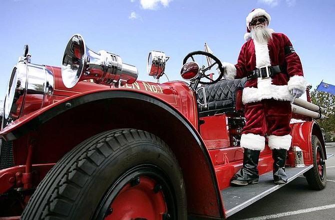 Chad Lundquist/Nevada Appeal Dressed as Santa Claus, Ed Rhyne, 51, of Reno, stands on the side of a fire engine provided by the Warren Engine Company for the 20th annual toy run through Carson City on Sunday.