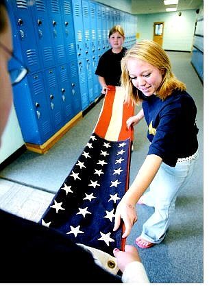 Cathleen Allison/Nevada Appeal Carson Middle School eighth-graders, clockwise from front, Robyn Gowan, Alyssa Brown and Shayna Ruybalidi, all 13, practice folding an American flag in preparation for Thursday&#039;s Veterans Day Commemoration program honoring former area military personnel.