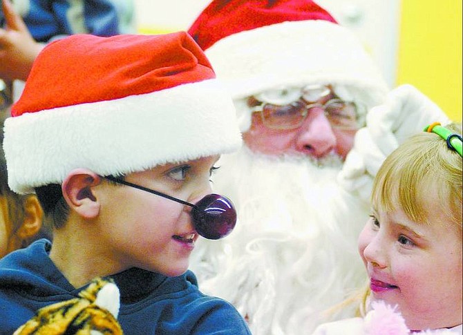 BRAD HORN/Nevada Appeal Tyler Roberts, 10, and Brianna Stark, 7, sits on Santa&#039;s lap during their party at Seeliger Elementary School.