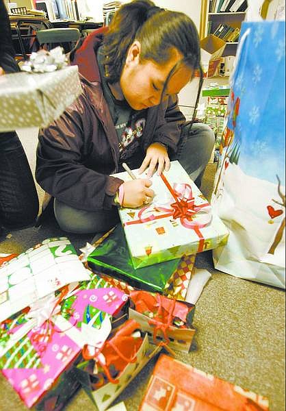 Cathleen Allison/Nevada Appeal Christy Lin, 16, puts tags on some of the gifts Carson High School Advanced Placement English students donated for a family they adopted for Christmas. Students raised money or donated gifts for the Carson City family of five.