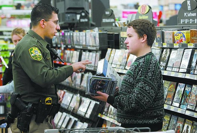 Cathleen Allison/Nevada Appeal Carson City Sheriff&#039;s Deputy Dan Gonzales helps James Jarrard, 13, calculate his gifts while shopping at Wal-Mart Monday morning. Volunteers helped area middle school students spend  $50 gift cards.