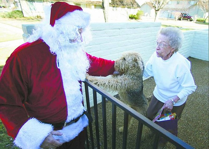 BRAD HORN/Nevada Appeal Santa Claus greets Hilda Christensen and her dog MacDuff at her Carson City home on Friday. Gwen Currie, of Friends to All, and Santa Claus brought gifts to the area&#039;s seniors including treats for their animals.
