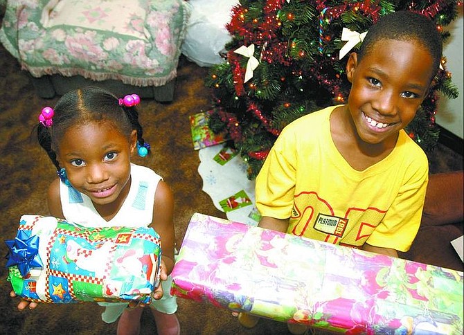 Kevin Clifford/Nevada Appeal Keaira, 4, and Keith Jr., 7, Robinson show off some of their Christmas presents Thursday in their Carson City home. The Robinson family is spending Christmas in Nevada, but they are making plans to move to Baton Rouge, La., in February.