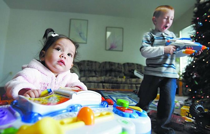 Ashlynn Durbin,10 months, plays with her 4-year-old brother Justin Schmidt&#039;s, right, foam darts at their home Christmas morning.  Chad Lundquist/ Nevada Appeal