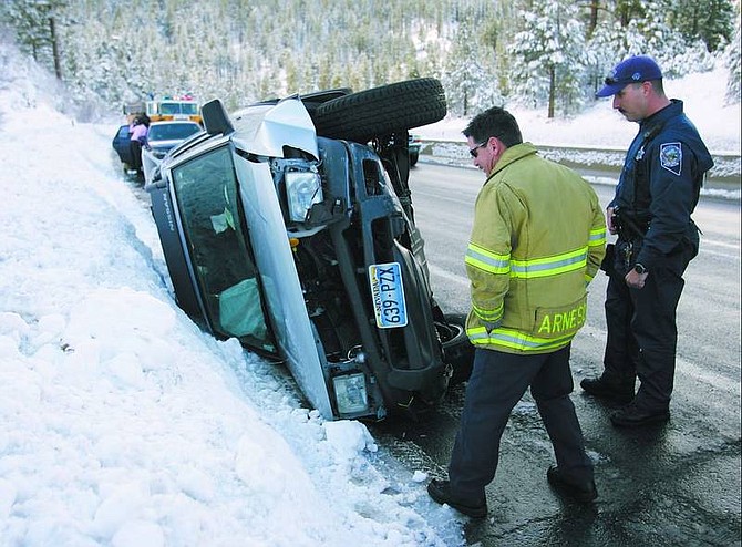 Chad Lundquist/Nevada Appeal Carson City firefighter John Arneson, left, and Nevada Highway Patrol Trooper Nick Nordyke look over a single-vehicle accident that occurred in the eastbound lanes of Highway 50 on Spooner Summit on Monday. The accident was the third on the highway that day, as icy conditions made driving hazardous at higher elevations.