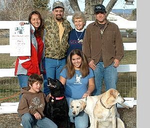 Brook Enos/Submitted photo Marshall Flag, top right, made the call that brought John Enos&#039; black lab, Belle, home. With Flag are the Enos family, from top left, Becky, holding a flier; Enos; his mother, Anne, Flag; lower left, his stepchildren Nicolas and Kaell with Belle and Flag&#039;s dogs Dallas and Sage.