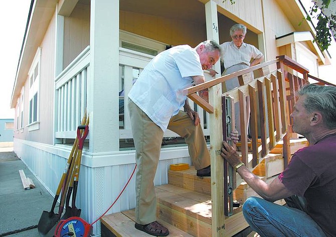 Chad Lundquist/Nevada AppealWith the help of Mike Clements, right, Laura and Gerald Denham add a set of steps to their new manufactured home off of Koontz Lane on Tuesday.