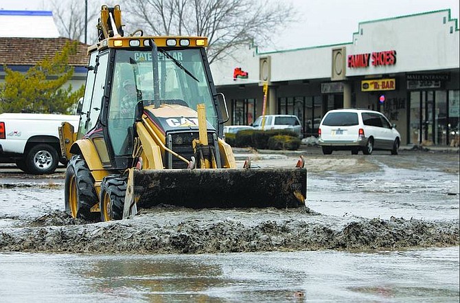 Heavy machinery is used to push standing water out of low-lying areas in the parking lot of the Carson Mall on Sunday.  Chad Lundquist/Nevada Appeal