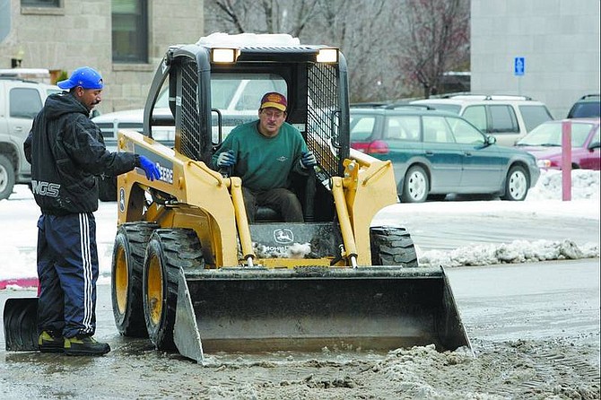 Chad Lundquist/Nevada Appeal Employees Santos Lopez and Arnie Palmas of Hanifin&#039;s Antiques work to clean mud and snow from the corner of Musser and Curry streets Tuesday. Hanifin&#039;s owner Michael Robbins, not pictured, rented the Bobcat to help with the cleanup effort.