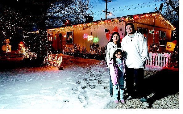 Chad Lundquist/Nevada Appeal Yadira Gomez, 21, left; Luis Fuentes, 23; and Jackie Fuentes, 5, stand outside their decorated house on Tenaya Drive Tuesday. The family won the annual &quot;Celebration of Lights&quot; contest sponsored by the Nevada Appeal and Meeks Lumber. They received a $100 gift certificate for Meeks.