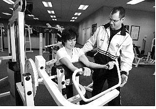Chad Lundquist/Nevada Appeal General Manager Nathen Hughes instructs Mary Jo Brummer on proper form Wednesday at Eagle Fitness. Brummer a longtime member of Silver State Fitness, was among those in need of a place to work out while repairs are made at the gym that was damaged Jan. 7 by 98-mph winds.