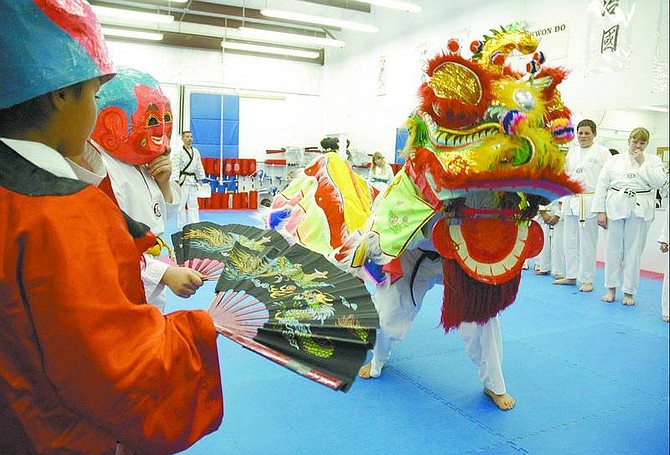 Kevin Clifford/Nevada Appeal Mikaela Jackson, 9, from left, and Dartanyan Perry, 10, perform the role of The God of Land while Paul Chung, 14, and Taylor Bradshaw, 11, perform the opening introduction of the Dragon Dance at Chi Kwan Tae Kwon Do on Friday night.