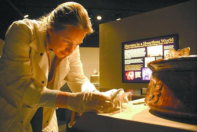 Kevin Clifford/Nevada Appeal Exhibit Preparator Jeanette McGregor carefully places a ceramic cherry toothpaste jar back on its stand after cleaning it Friday afternoon at the Nevada State Museum. The jar is just one of many artifacts found from Virginia City that will be shown at the &quot;Havens in a Heartless World&quot; exhibit starting Tuesday.