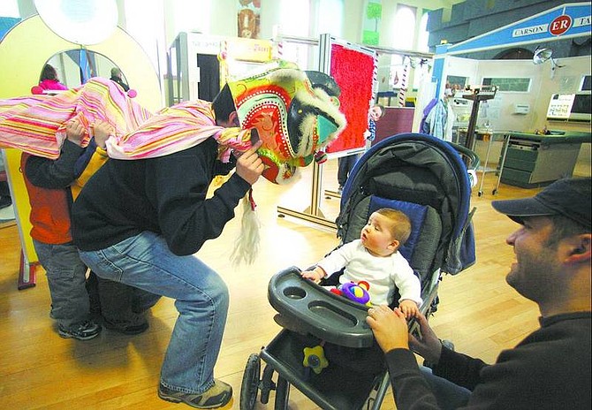 BRAD HORN/Nevada Appeal Miles Pishotti, 6 months, is greeted by Yunfeng Zhang playing the head of the dragon as part of the Chinese New Year celebration Saturday at the Children&#039;s Museum of Northern Nevada. Miles&#039; father, Anthony, is pictured at right.