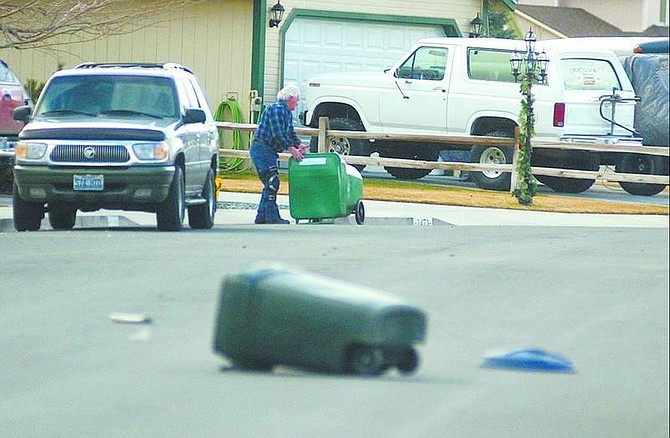 BRAD HORN/Nevada Appeal A man picks up his trash can on Colorado Street after wind gusts blew several trash cans and recycling crates into the street on Wednesday.