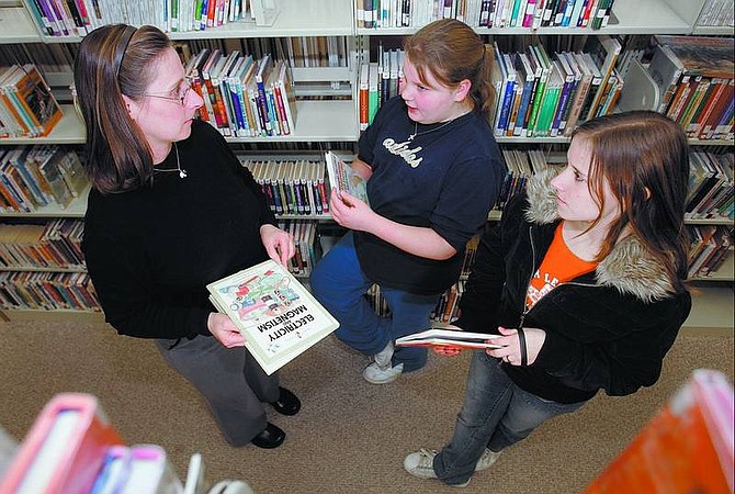 Chad Lundquist/Nevada Appeal Dayton Valley Library manager Theresa Kenneston talks with students Hailey Ortez, 11, middle, and Lorna Richardson, 15, about their science fair projects on Tuesday at the Dayton Library.