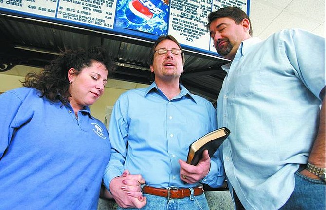 Chad Lundquist/Nevada Appeal Philadelphia Cheesesteak Co. owners Dawn Brenneis, left, and Jim Brenneis, far right, pray with the Rev. Pat Propster of Calvary Chapel as he blesses their business Tuesday. The Brenneises have been a Christian family for many years and wanted to bring the same atmosphere into their business.