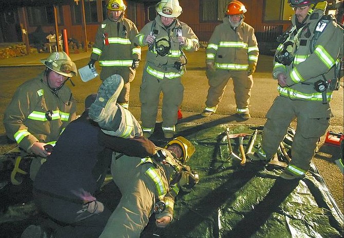 Kevin Clifford/Nevada Appeal Firefighter/Paramedic Bob Ryser uses volunteer firefighter Theddeus Coughnan as a simulated victim Thursday night to show how to properly secure a downed firefighter. The demonstration was part of a training session at the former Dayton Parkview Adult Residence.