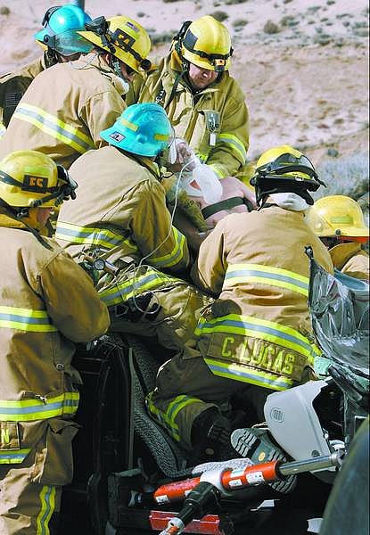 Chad Lundquist/Nevada Appeal Firefighters from Carson City and Tahoe-Douglas fire departments work to remove 54-year-old David Ryan, of Zephyr Cove, from his vehicle Sunday morning on Highway 50 West, following a collision into a parked trailer.