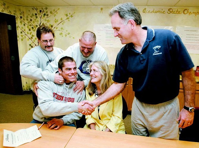 Cathleen Allison/Nevada Appeal After signing a letter of intent to play for Southern Oregon, Eric Walthers gets congratulated by Carson High football coach Shane Quilling, right, as coaches Jim Franz, Jim Bean, and his mom Sheila joke with him.