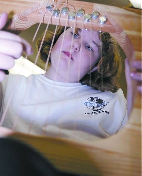Chad Lundquist/Nevada Appeal Thirteen-year-old Kathleen Bryant practices &quot;Aura Lee&quot; on her handmade harp Wednesday afternoon at Carson Middle School. A team of 15 students from the middle school will compete in the state Science Olympiad on Saturday at Western Nevada Community College.