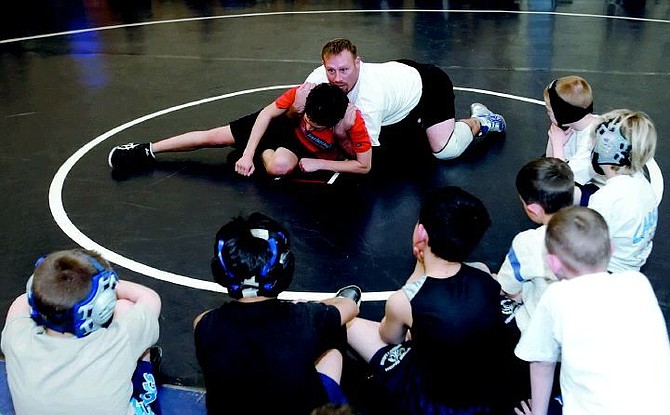 Chad Lundquist / Nevada Appeal Carson wrestling coach Casey Schweitzer demonstrates a basic wrestling move to kids from the Carson Bulldog Wrestling Club on Tuesday.