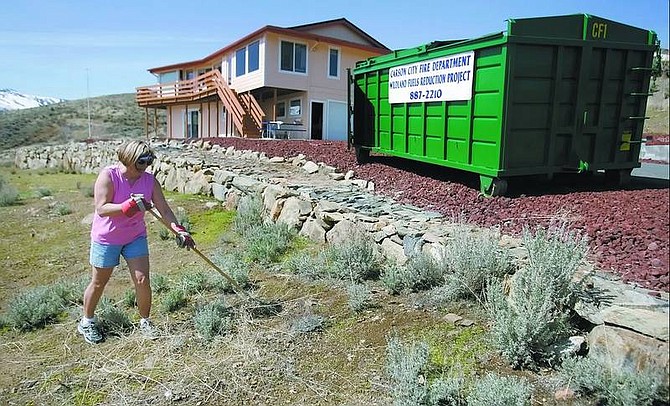 Chad Lundquist/Nevada Appeal Pat Wentworth, 55, works to clean up the dead mustard plants that have taken over her yard at her home in north Carson City on Sunday. Wentworth agreed to have a trash receptacle on her property as part of an initiative to help protect homes from wildfires.