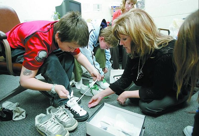 Kim Riggs, right, director of the Carson City School  District&#039;s Children-in-Transition program, helps  students at Fritsch  Elementary school try on new tennis shoes Monday. Fifty  students received a new pair of shoes through the district&#039;s Easter shoe drive, which still needs donations.   Chad Lundquist/ Nevada Appeal