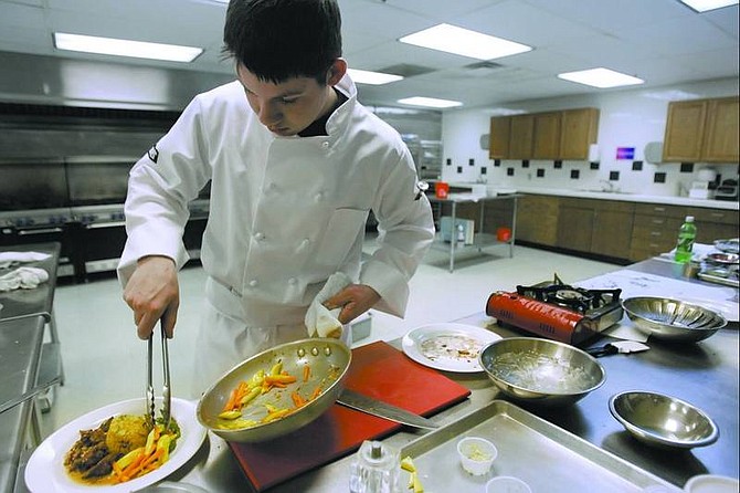 Chad Lundquist/Nevada Appeal Andrew Coleman places vegetables on an entr&#233;e of ostrich tenderloin and couscous Monday after school at Carson High School. Andrew and three of his classmates will go to the national culinary competition April 29-May 4 in Charlotte, N.C. The menu will include this dessert, right,  of champagne mousse with strawberries and kiwi atop an oats-and-pecan crust and topped by a handmade chocolate butterfly.