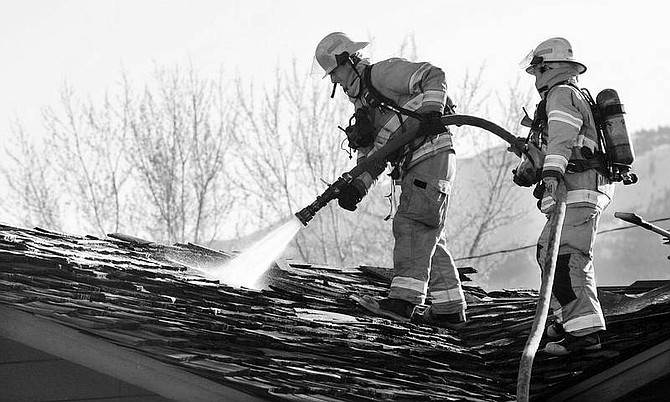 Chad Lundquist/Nevada Appeal Carson City firefighters work to put out a fire in the attic at a home in the 3000 block of Imperial Way on Sunday evening.