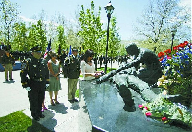 Dawn Prendes, center, widow of Sgt. Henry Prendes of the Las Vegas Metropolitan Police Department, places a baton at the Nevada Law Enforcement Officers Memorial during the ceremony in Carson City on Thursday. The baton holds the 101 names of Nevada law enforcement officers who were killed in the line of duty.