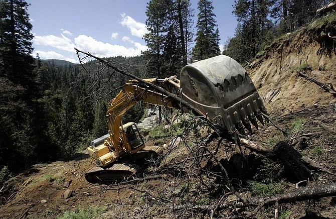 Rich Pedroncelli/Associated Press An excavator removes a fallen tree as it digs through a mudslide on Highway 50 near Kyburz, Monday. No one was injured and no homes were threatened, when the slide occurred Sunday.