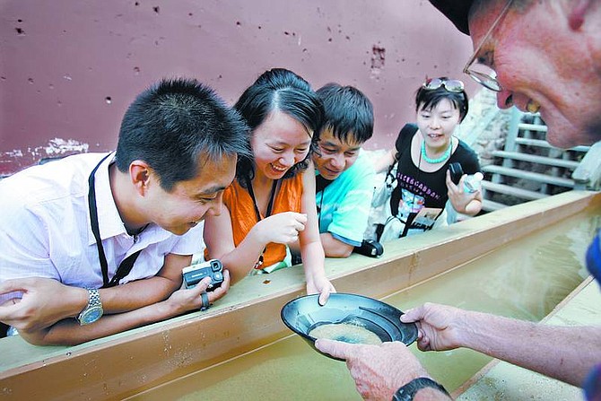 Chad Lundquist/Nevada AppealFrom left, Xia Yan, Yang Shuangyan, Zhou Tao, and Jessie Zheng look on excitedly as Vance Millett, 63, shows a group from China a few small flakes of gold at the bottom of a pan, at a gold-panning attraction on C Street in Virginia City. The Nevada Commission on Tourism was hosting Monday&#039;s tour in hopes of stimulating tourism commerce with China.