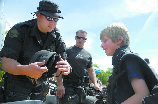Kevin Clifford/Nevada Appeal Mike Fischer, SWAT team leader, left, and Chris Rivera, SWAT operator, show Brandon Thielmann, 7, the gear that is  used by the team. The demonstration was part of the annual Cops and Kids Open House at the Carson City Sheriff&#039;s Department on Saturday morning.