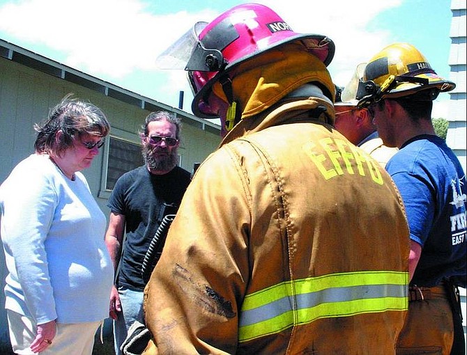 Aretta and Chris Koch are briefed by firefighters on Tuesday morning after their Topaz Ranch Estates home burned.   Jonni Hill/Appeal News Service