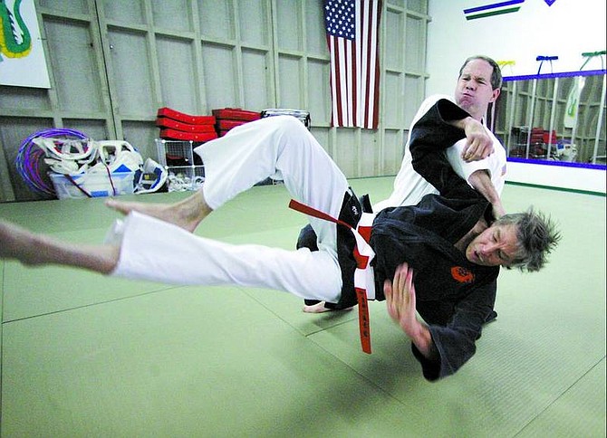 BRAD HORN/Nevada Appeal John Chatwood, an eighth-degree black belt in Jujitsu, demonstrates a knee throw into a ground control move (a choke) with lead instructor and fifth-degree black belt Charles &quot;Chaz&quot; Carter, at Sierra Jujitsu/Karate on Thursday.