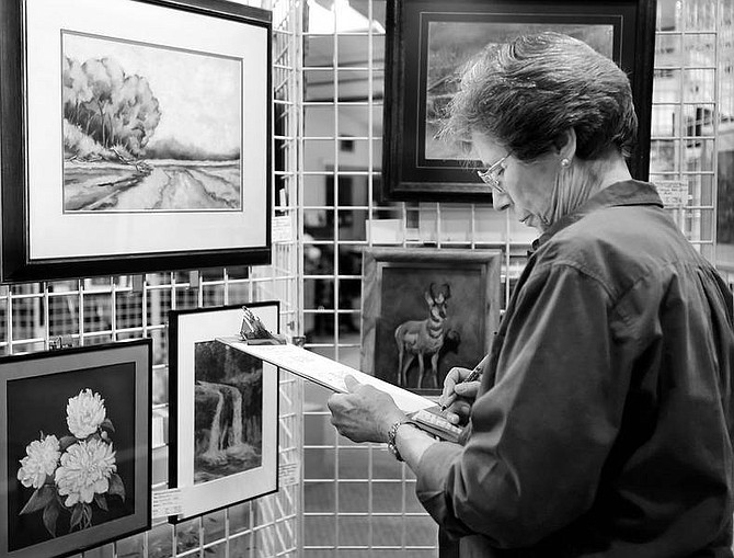 Chad lundquist/Nevada Appeal Nevada Artists Association summer art show judge Ann Pierce looks over some of the entries at the Brewery Arts Center Sunday. The show is one of three annual juried events by the association to allows its 150 members to show off their best works.