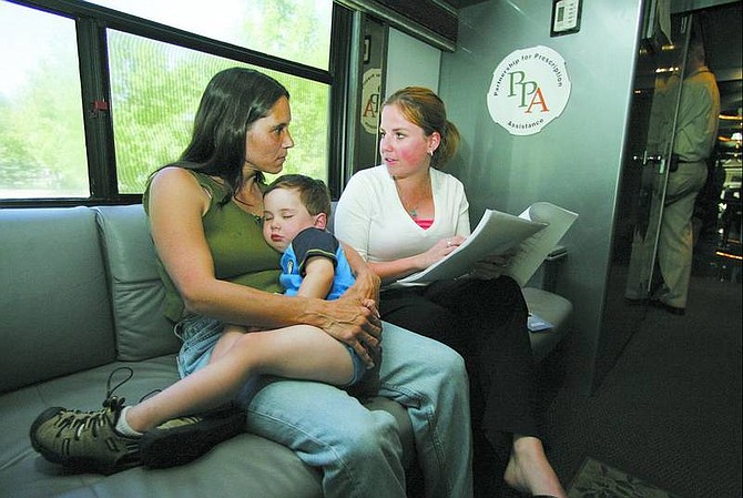 BRAD HORN/Nevada Appeal Jessica Wilson, right, a Partnership for Prescription Assistance field staff member from Lexington, Ky., helps Kimberly Sanchez and her very sleepy son Tyler Fisher, 2, find cheaper alternatives to buying prescription drugs on the organization&#039;s bus on Wednesday.