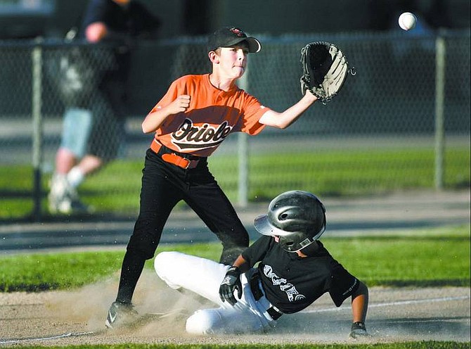 Cathleen Allison/Nevada Appeal  T.J. Thomsen of the Rockies slides safely under the Orioles third baseman Tyler Valley during Thursday night&#039;s Carson City Little League Majors championship game at Governor&#039;s Field.
