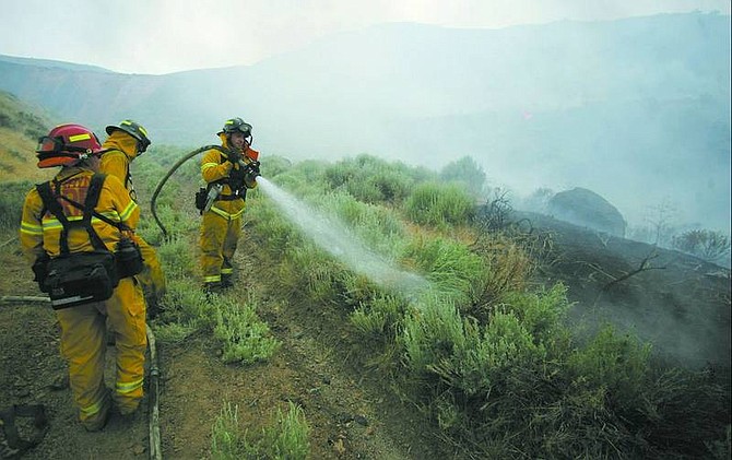 BRAD HORN/NEVADA APPEAL Firefighters douse hot spots on the Linehan Complex fire in Carson City on Wednesday. The fire burned 4,500 acres from Mound House to Goni Canyon.
